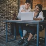 Image of woman with a prosthetic leg working in an office with a colleague.