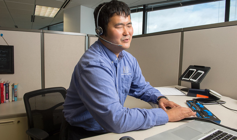 Image of a man using accessible technology in an office workstation.