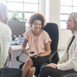 Image of diverse group of individuals conversing a workplace, including one woman who uses a wheelchair.